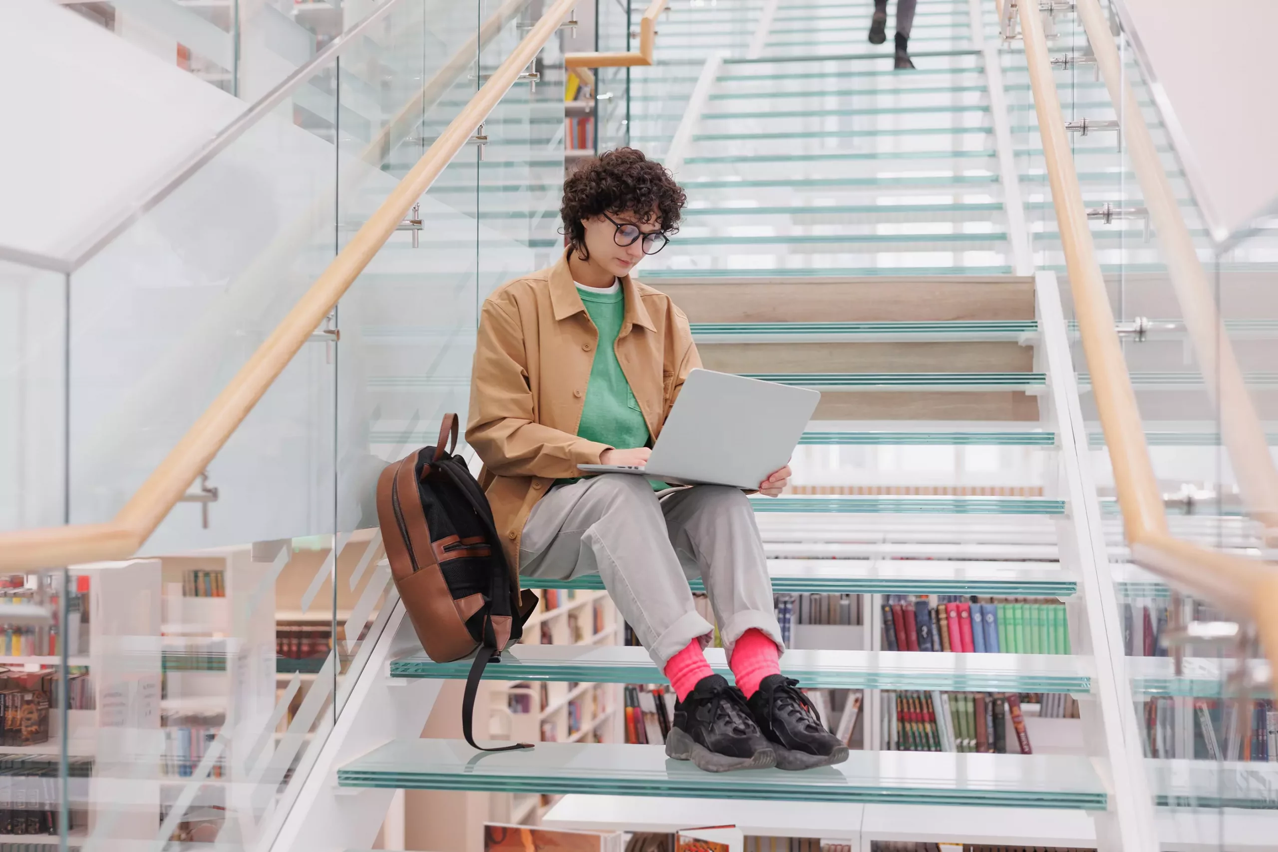 кудрявая женщина на ступенях университета с ноутбуком
