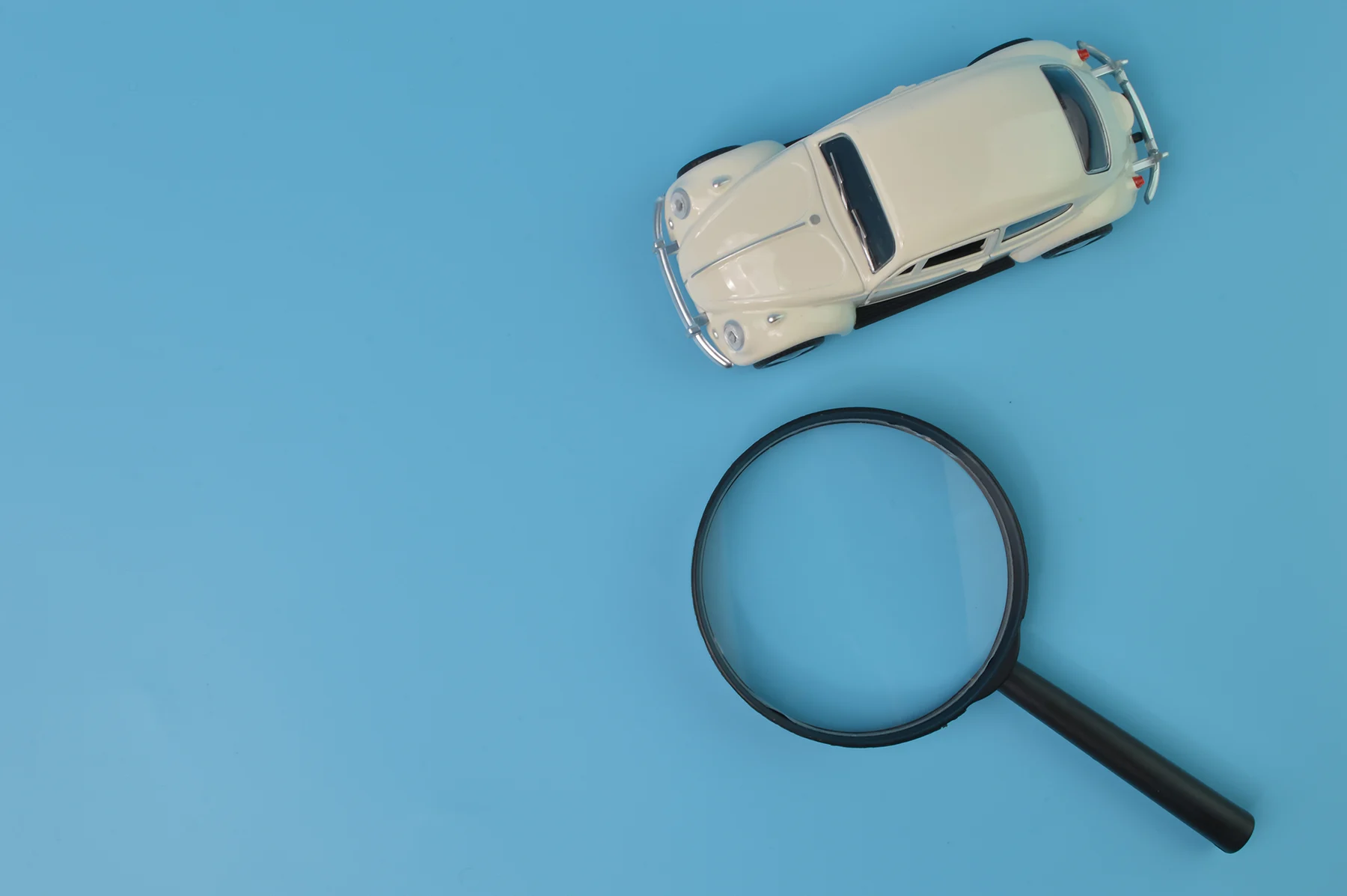 white-retro-car-model-and-magnifying-glass-find